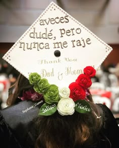 a person wearing a graduation cap with flowers on it's head and writing in spanish