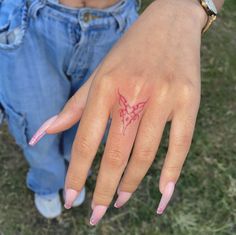 a woman's hand with a butterfly tattoo on her left thumb and pink fingernails