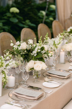 a long table is set with white flowers and silverware for an elegant wedding reception