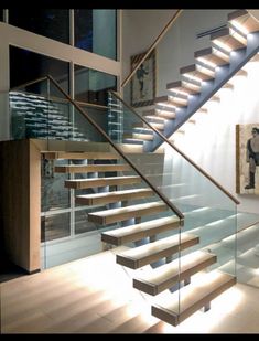 a stair case with glass railing and wooden handrails in a modern style home