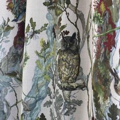 an owl sitting on top of a tree branch in front of a curtain with leaves and flowers