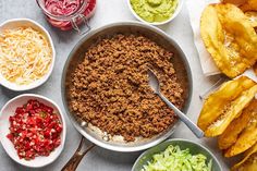 several bowls with different types of food in them on a table next to potato chips and guacamole