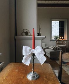 a candle with a bow on it sitting on a table in a living room next to a couch