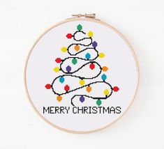 a cross stitch christmas tree with lights on it