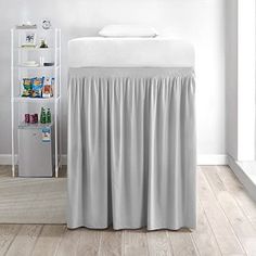 a bed with a white headboard and grey drapes on the top of it