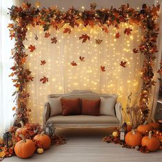 a living room decorated for fall with pumpkins and leaves on the wall, couches and lights