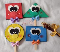 four different colored paper crafts on sticks with bows