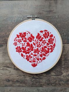 a red and white embroidered heart on a wooden surface