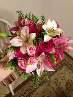 a bouquet of pink and white flowers sitting on top of a table next to a chair