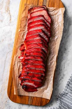 sliced up meat sitting on top of a wooden cutting board