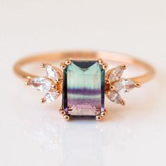 The most dreamy fluorite center is paired with petal inspired CZs in this gorgeous ring from La Kaiser.  Set in rose gold, these feminine colors beautifully balance the organic feel of the fluorite. This style is a Local Eclectic exclusive! Fluorite 8 x 6 mm Cubic zirconia 1.5 x 3.5 mm 18k rose gold vermeil plated Ster Watermelon Tourmaline Engagement Ring, Fluorite Jewelry, Fluorite Ring, Tourmaline Engagement Ring, Cut Watermelon, Local Eclectic, Bling Ring, Marquise Diamond Ring, Wedding Rings Solitaire