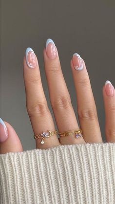 a woman's hand with pink and white manicures on her nails, wearing a gold ring