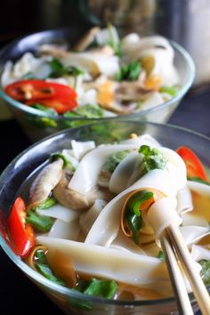 two clear bowls filled with noodles and vegetables