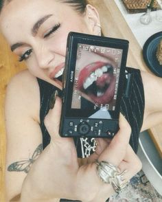 a woman holding up a cell phone to take a selfie with her mouth open