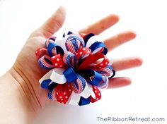 a hand with a red, white and blue hair bow on it's palm