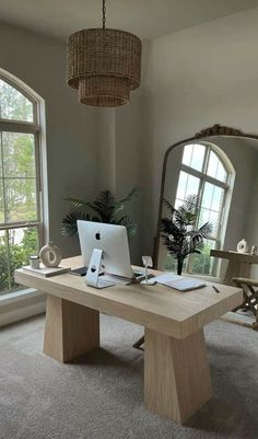 a desk with a laptop on it in front of a window and a large mirror