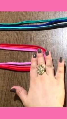 a woman's hand with two rings on her fingers next to several colored ribbons