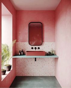 a bathroom with pink walls and white counter tops, in the middle of a room