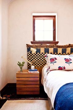 a bedroom with a bed, dresser and window in it's corner next to a painting on the wall