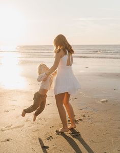 a mother and son playing on the beach at sunset