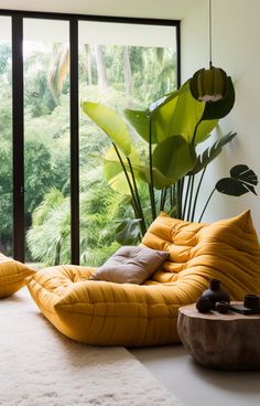 a living room filled with lots of furniture next to a large glass window covered in greenery