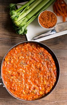 a pan filled with food next to carrots and celery