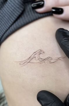 a woman's stomach with a wave tattoo on it