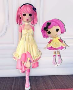 two dolls are standing next to each other in front of a white wall and pink carpet