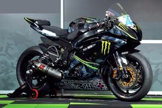 a monster motorcycle is parked in front of a gray wall and green checkered floor