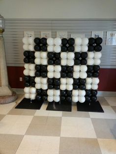 black and white balloons are arranged in the shape of a number on a checkered floor