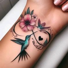 a humming bird with flowers on its arm