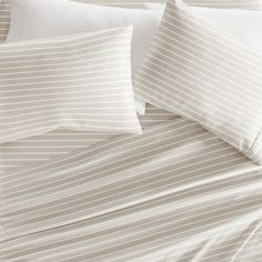 an image of a bed with white and beige striped comforter set on top of it