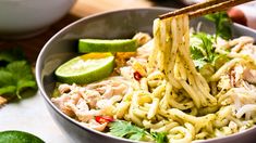 a bowl filled with noodles, chicken and garnished with cilantro sauce