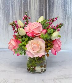 a vase filled with pink and white flowers on top of a marble counter next to a window