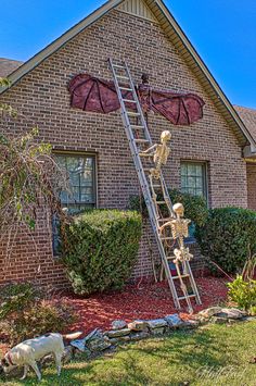 a house with a statue of a skeleton on the roof and a ladder leading up to it