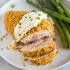 a white plate topped with meat and asparagus