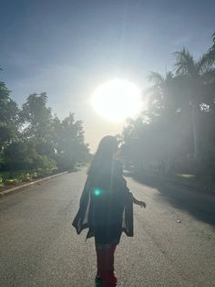 a woman is walking down the street in the sun