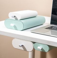 an open laptop computer sitting on top of a white desk next to two rolled up books