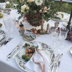 the table is set with plates, silverware and flowers in vases on it