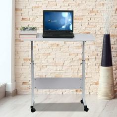 a laptop computer sitting on top of a white table next to a vase with flowers