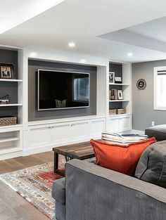 a living room filled with furniture and a flat screen tv mounted on the wall above it