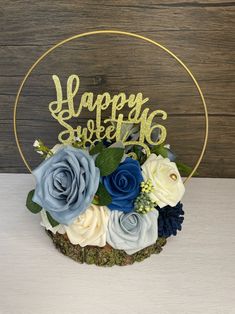 a happy sweet 16 cake topper surrounded by blue and white flowers on a wooden table