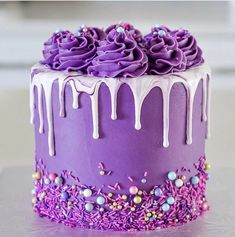 a purple cake with white icing and sprinkles on it's side