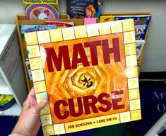 a person holding up a book with the words math curse on it in front of bookshelves