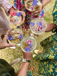 four people holding wine glasses with flowers on them