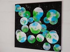 a painting hanging on the wall with green and blue circles in it's center