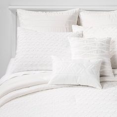 a bed with white sheets and pillows on it