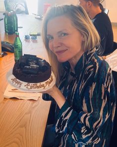 a woman sitting at a table with a chocolate cake