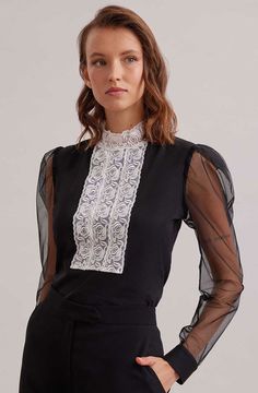 The EPOPEE is a black jersey pullover top with a center ribbon appliqué front made of a triple lace rose column that extends to create a mock neck. The pleated shoulders give way to a voluminous sheer sleeve that are finished with black jersey single French cuffs that allow for cufflinks. The EPOPEE features a hidden zipper at the back for closure. Style Nr.H22F053 Hidden zipper at the back for closure Body: 92% Cotton, 8% Elastane; Sleeves: 100% Polyester; Collar: 100% Polyamide Jersey cotton i Black Jersey, Mock Neck Top, Fall Coat, Long Puff Sleeves, Lace Panelled, Sheer Sleeves, Shoes Heels Boots, Puff Sleeves, Hidden Zipper