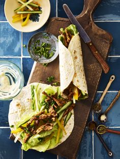 two tacos with meat and vegetables on a cutting board